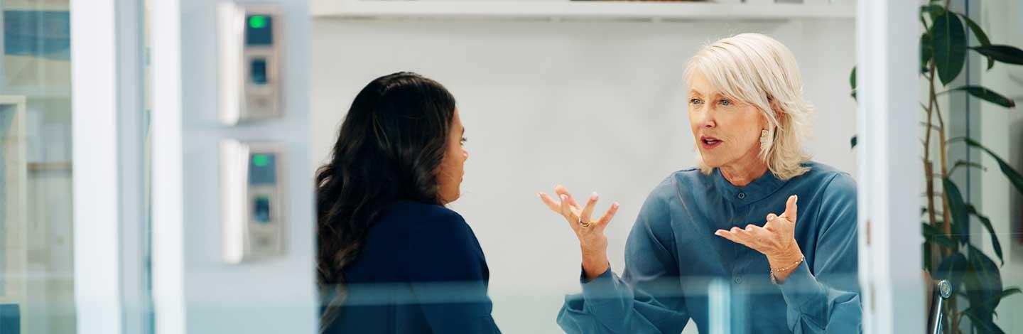 Meeting between two female workers in an office location.